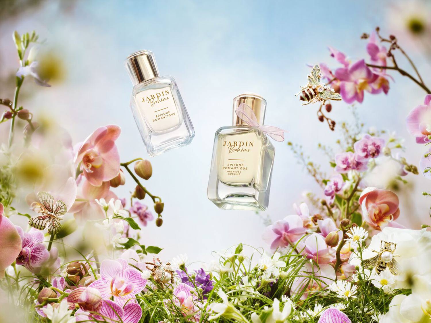 Deux flacons de parfum Jardin Bohème Épisode Romantique flottent au milieu d'un arrangement floral vibrant, avec des touches d'orchidées roses et de marguerites blanches.