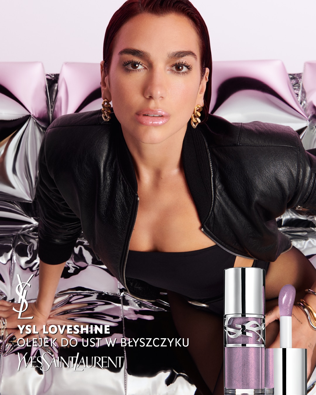 Na srebrnym tle Dua Lipa prezentuje błyszczyk YSL Loveshine o delikatnym, fioletowym odcieniu, który dodaje ustom subtelnego blasku.
