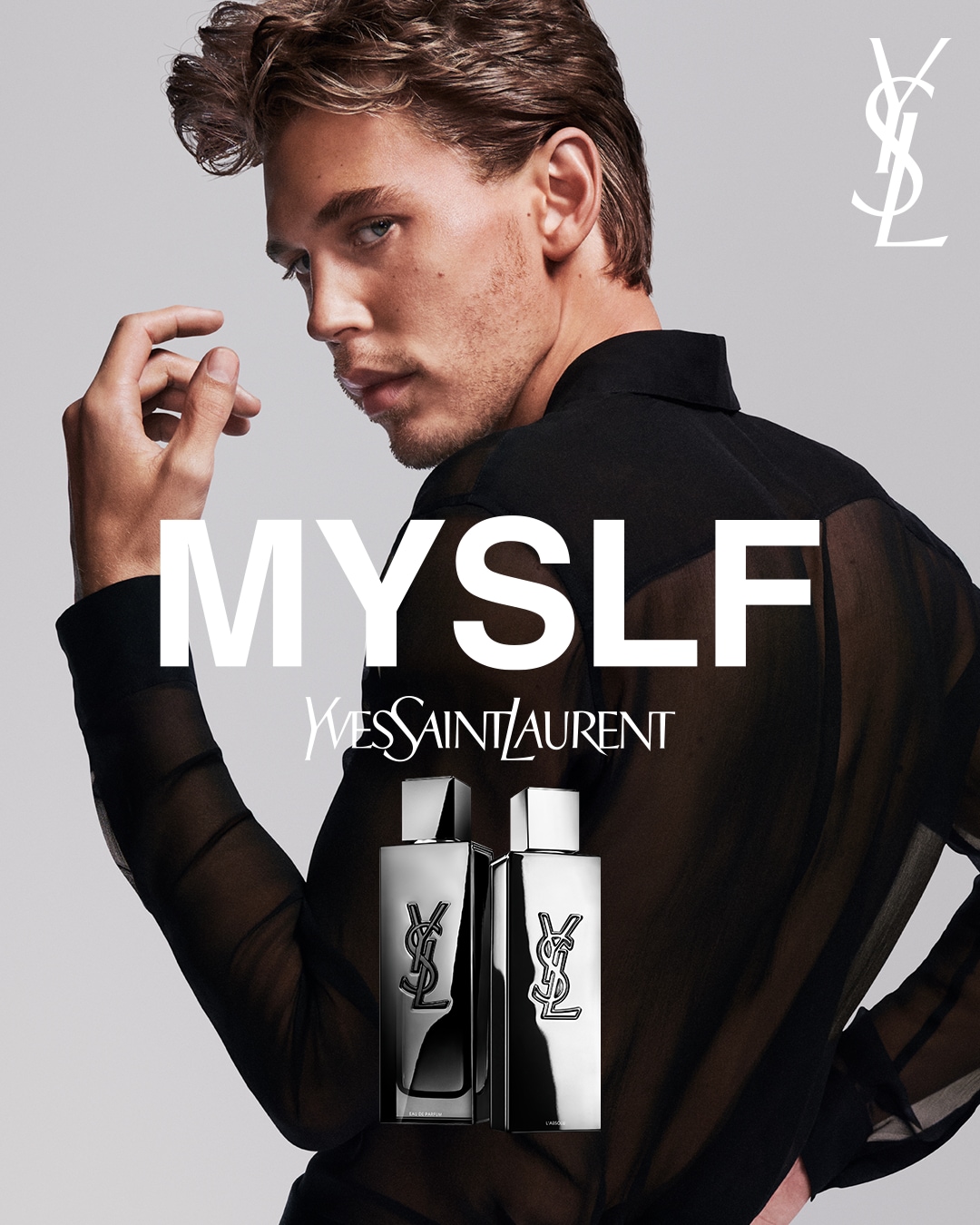 Na szarym tle widać mężczyznę w czarnej, prześwitującej koszuli, a obok niego flakony perfum Yves Saint Laurent MYSLF w srebrnych opakowaniach z czarnym logo YSL.