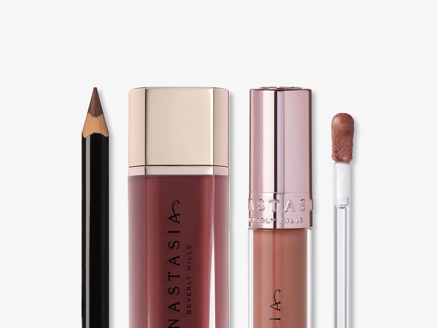 Mehrere Anastasia Beverly Hills Lippenprodukte: Ein brauner Lipliner, ein bordeauxroter Lippenstift mit goldenem Deckel und ein nude-farbenes Lipgloss mit roségoldenem Deckel.