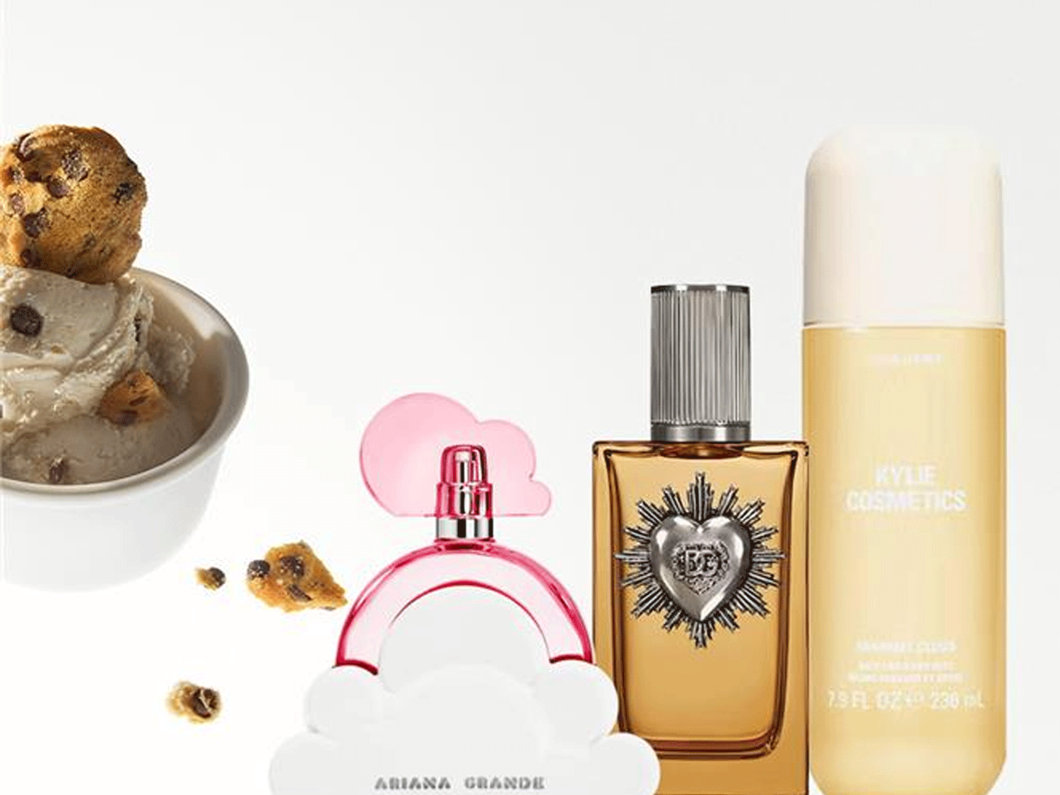 Nuotraukoje matomi kvepalai „Ariana Grande Cloud“, „Juicy Couture“ ir „Kylie Cosmetics“ aliejus šalia ledų su sausainiais.