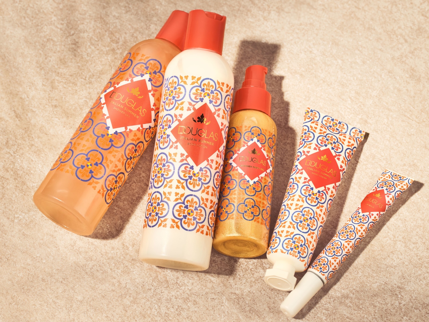 Découvrez l'ensemble de soins corporels Douglas Italian Summer, comprenant un gel douche, une lotion pour le corps, une huile scintillante, une crème pour les mains et un baume à lèvres, tous dans un emballage orné de motifs italiens.