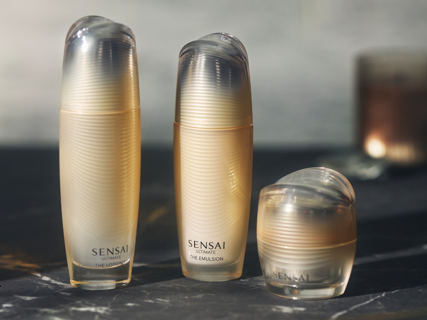 Découvrez Sensai Ultimate, une lotion et une émulsion dans des flacons élégants aux teintes dorées et aux bouchons transparents, pour une peau sublimée.