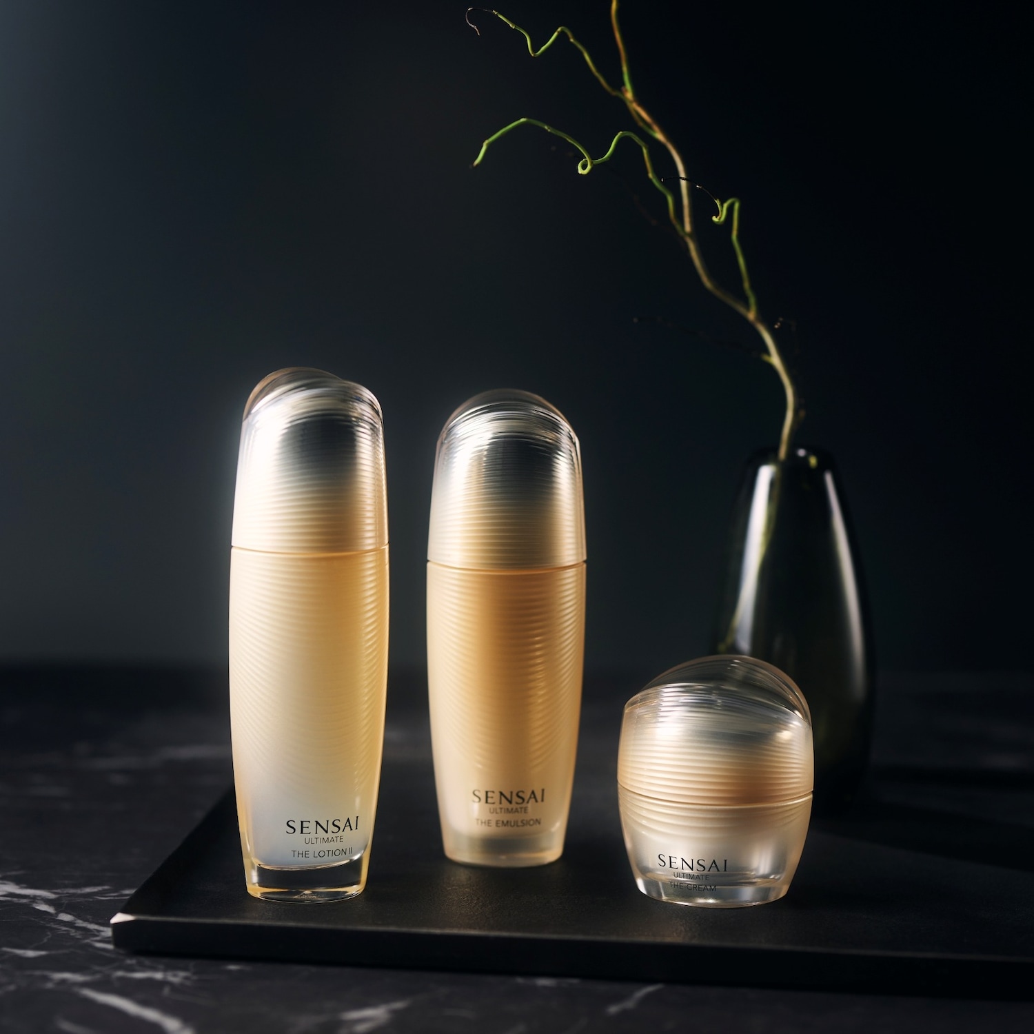 Découvrez Sensai Ultimate, une collection de soins de la peau de luxe présentée dans des emballages élégants aux tons dorés, comprenant une lotion, une émulsion et une crème.