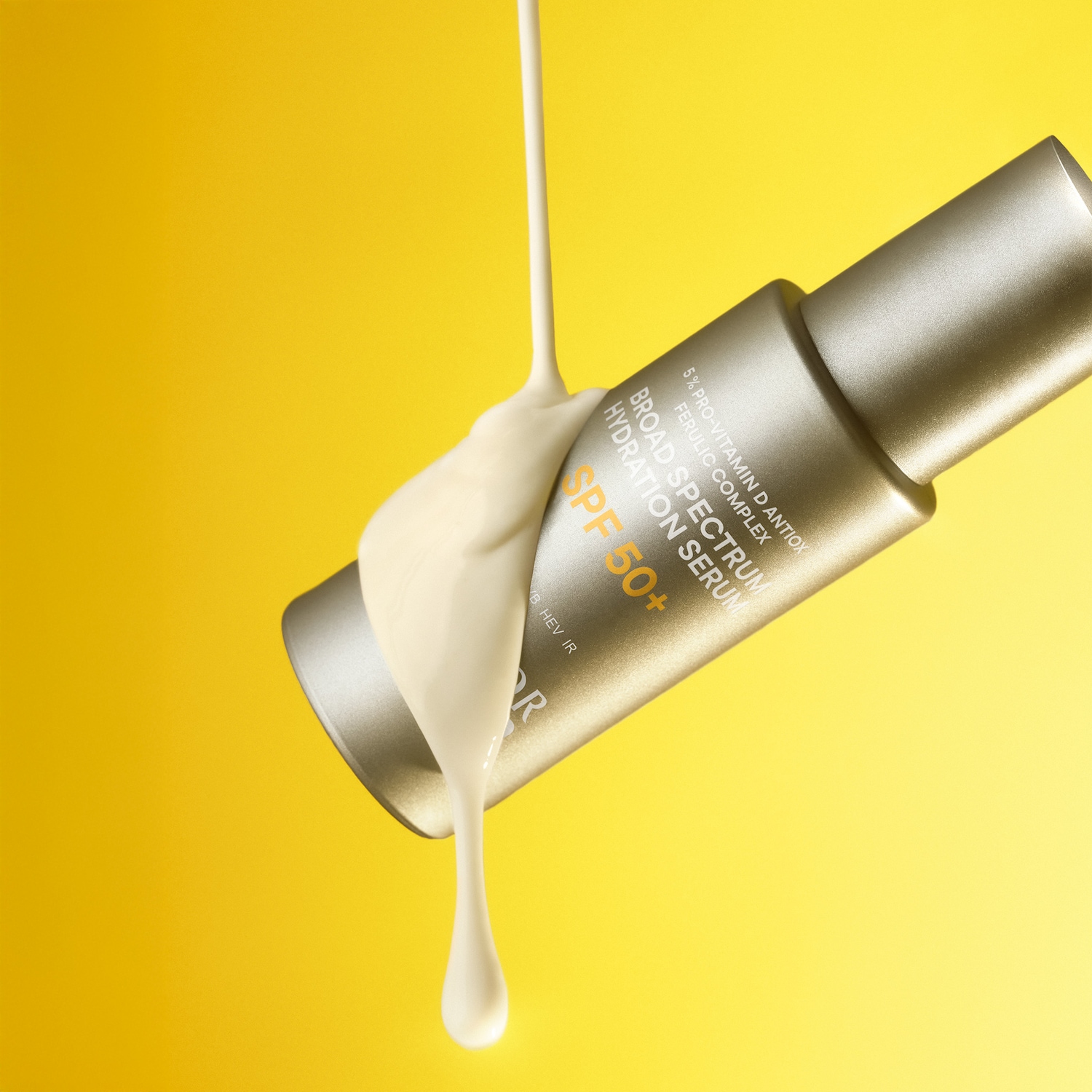 Auf gelbem Grund fließt eine cremefarbene Flüssigkeit über eine goldene Serumflasche mit der Aufschrift „Breitspektrum-Hydratationsserum LSF 50+“.