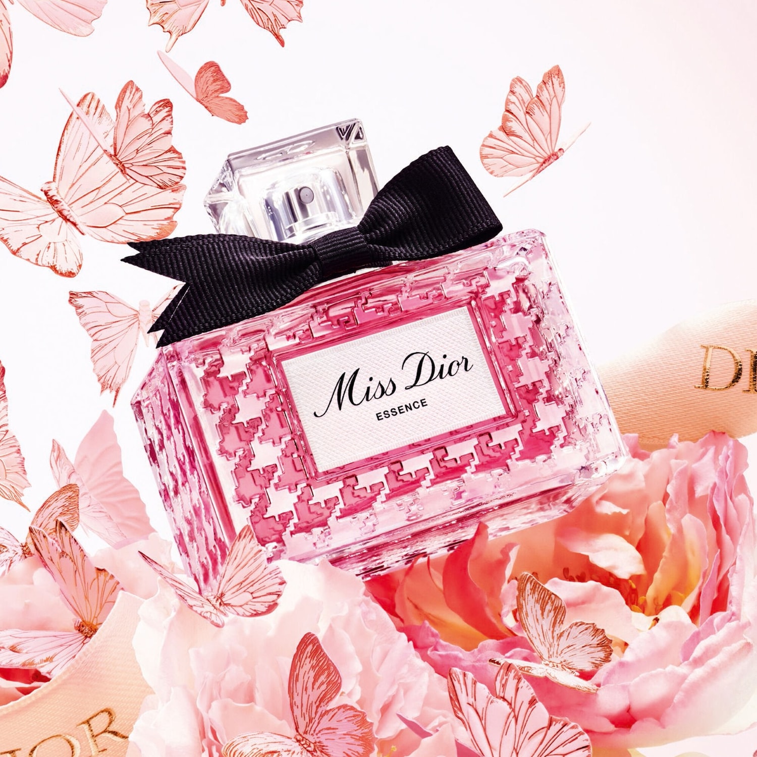 Le flacon de parfum Miss Dior Essence rose est orné d'un nœud noir, entouré de fleurs et de papillons roses.