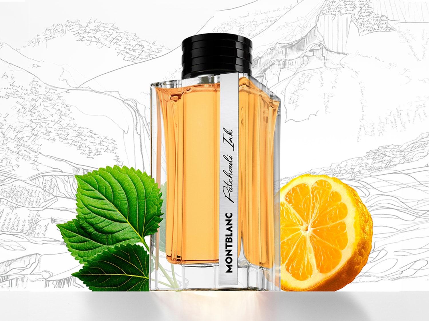 Butelka Montblanc Patchouli Ink z jasnożółtym płynem, ozdobiona liśćmi i połówką pomarańczy na tle szkicu górskiego.