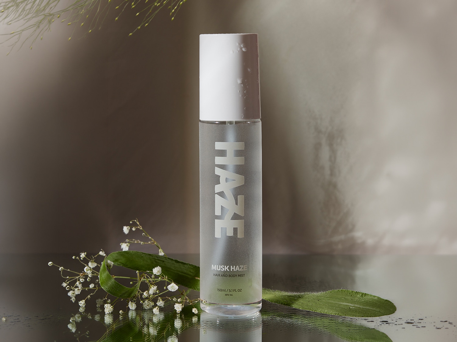 Ecco una bottiglia di spray per capelli e corpo Musk Haze, con confezione trasparente e scritte bianche, adatta per idratare e profumare delicatamente la pelle e i capelli.