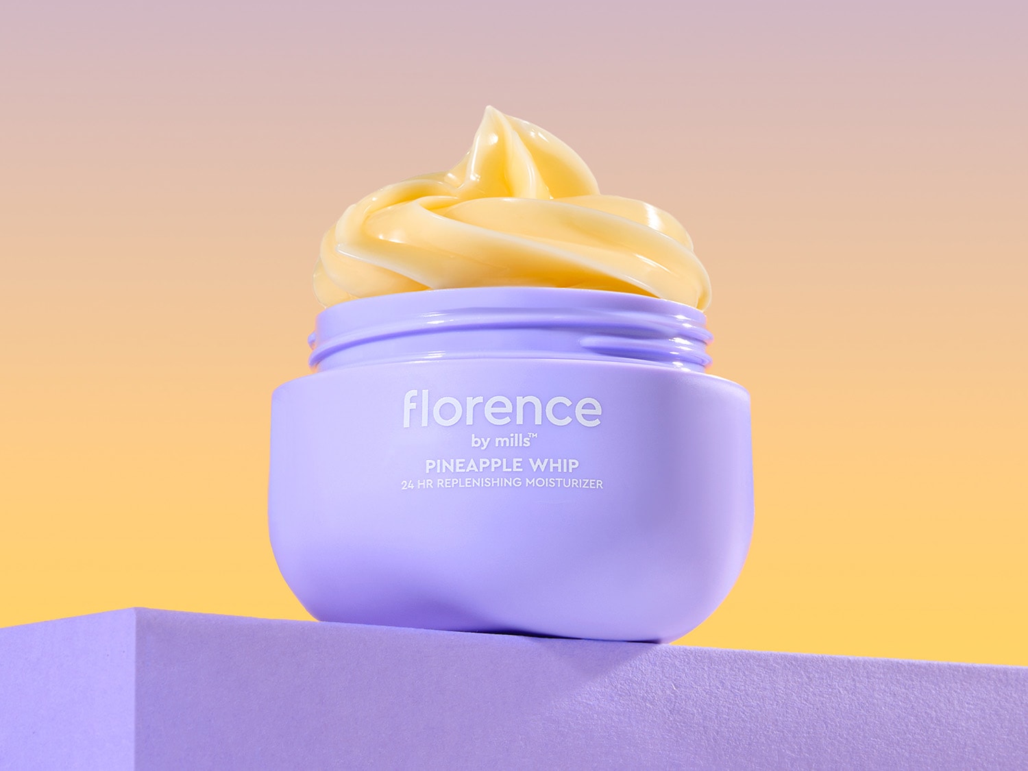 Štai „Florence by Mills“ „Pineapple Whip“ 24 valandų papildomas drėkiklis violetiniame indelyje su geltonu kremu viršuje, ant violetinio pagrindo.