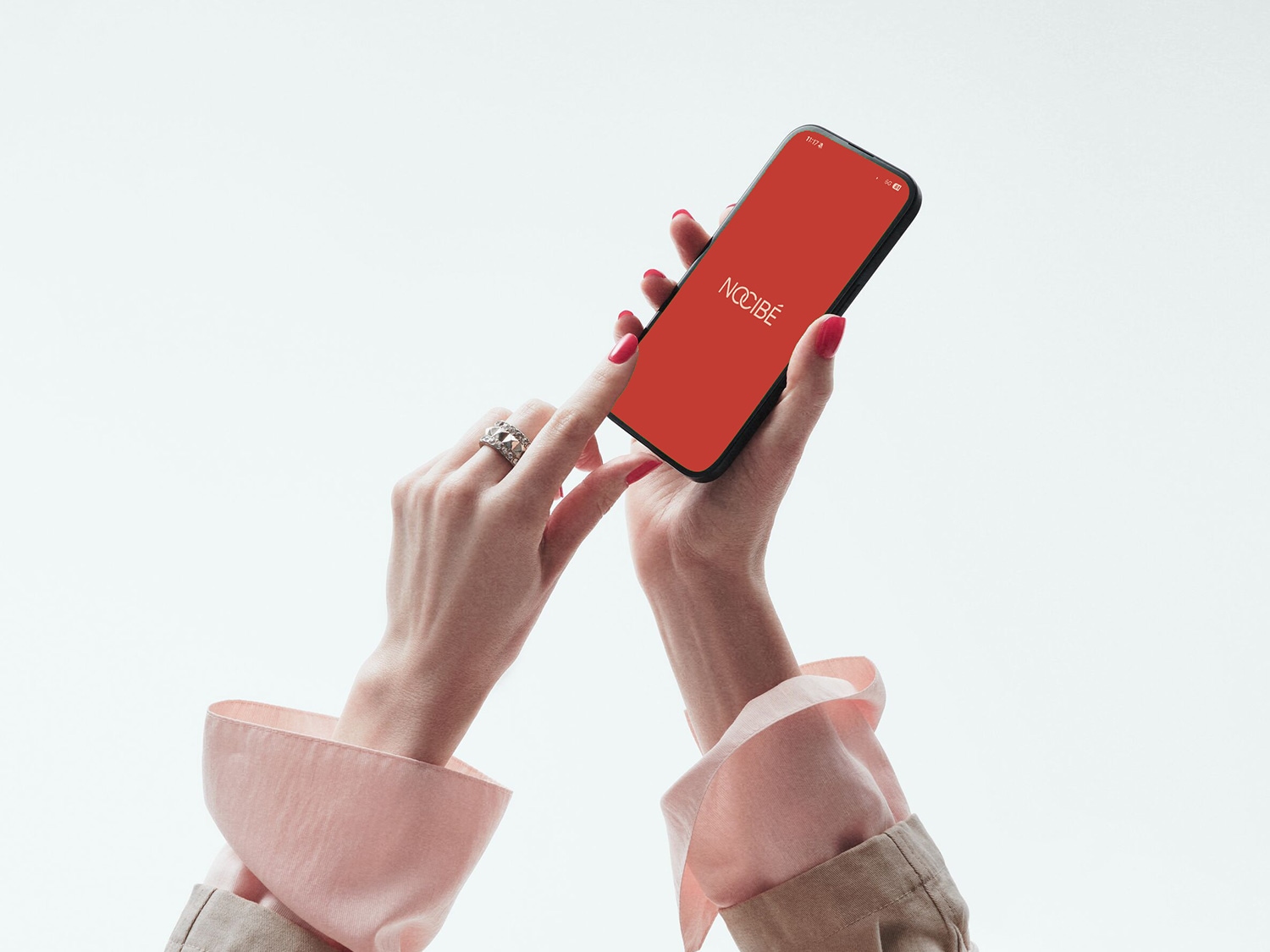 Gros plan sur une femme tenant un smartphone avec l'application Nocibé affichée sur un écran rouge vif, prête à explorer un univers de beauté.