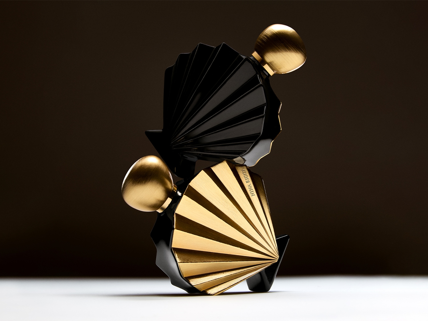 Voici Nina Ricci L'Extase Rose Absolue, un parfum avec un flacon noir et or en forme d'éventail et un bouchon doré en forme d'œuf.