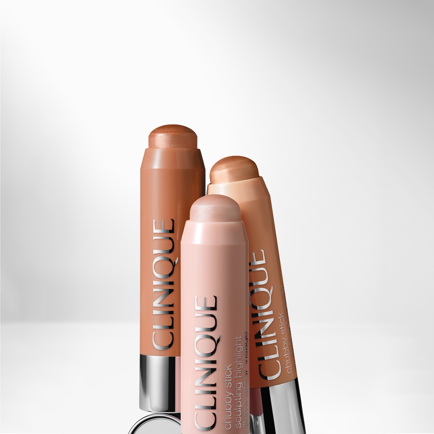 Nahaufnahme von drei Clinique Chubby Sticks Sculpting Highlight in verschiedenen Farbtönen vor hellem Hintergrund.