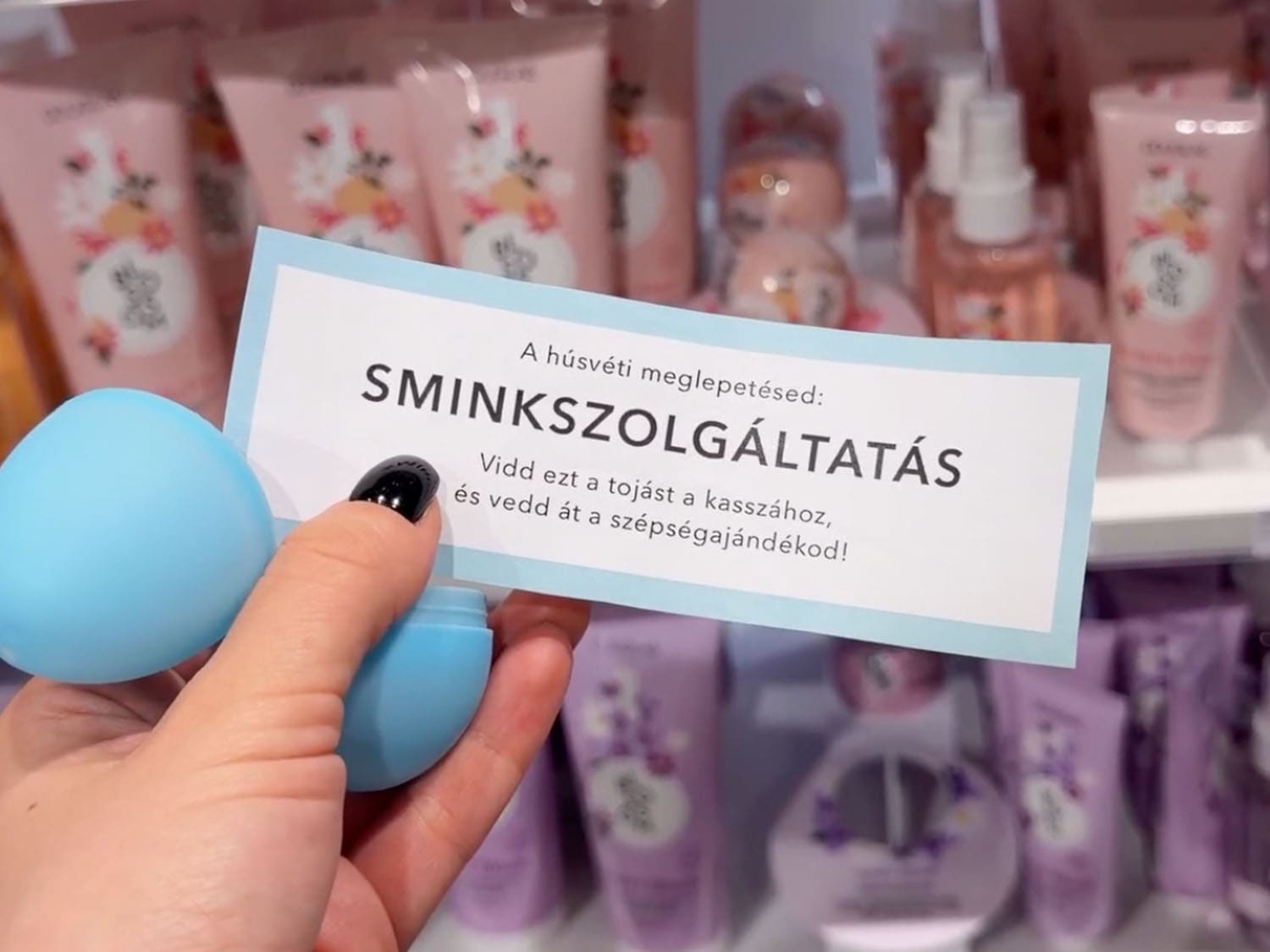 Hand holds a light blue egg-shaped container next to a sign that reads 'SMINKSZOLGÁLTATÁS', inviting customers to redeem the egg at the checkout for a beauty gift.