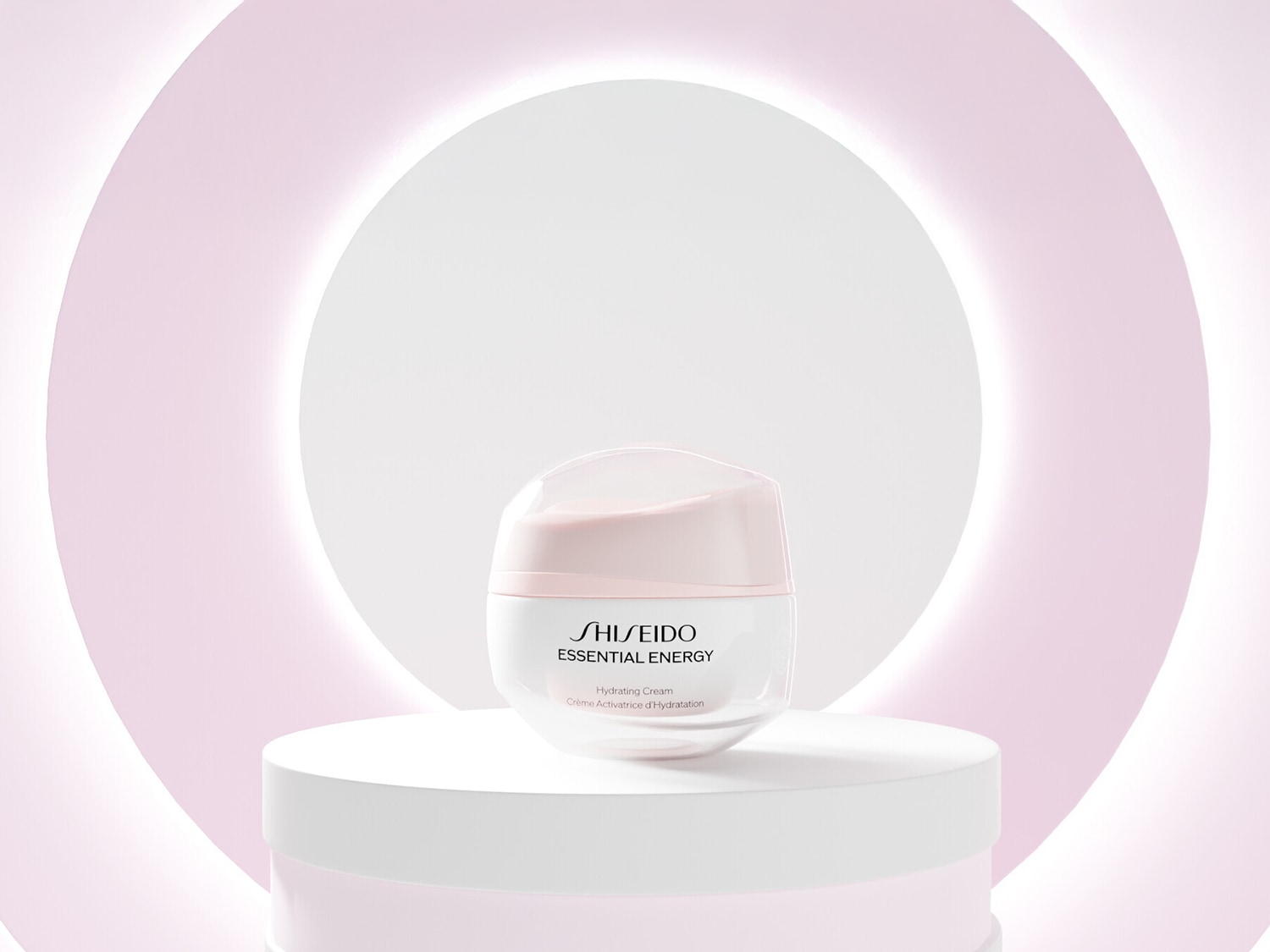 Auf einem weißen Podest steht die Shiseido Essential Energy Feuchtigkeitspflege in einem weißen Tiegel mit rosafarbenem Deckel vor einem hellrosa Hintergrund.