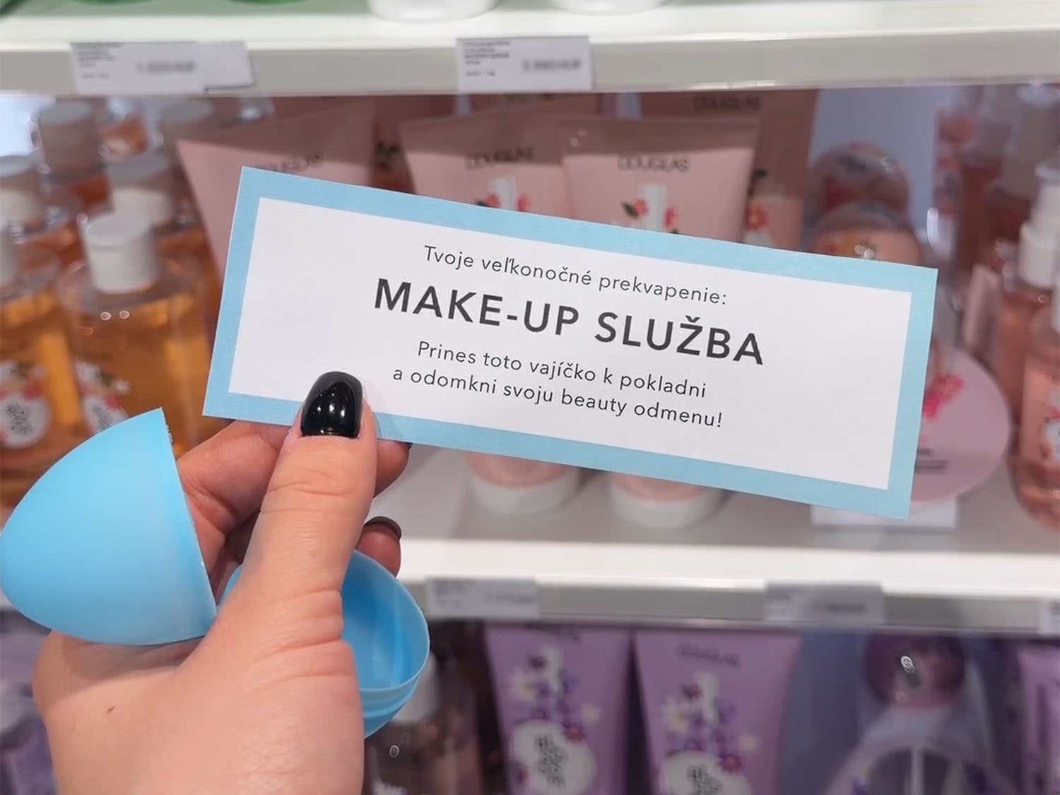 Hand holds a light blue plastic egg next to a sign that reads 'Your Easter surprise: MAKE-UP SERVICE. Bring this egg to the checkout and unlock your beauty reward!'