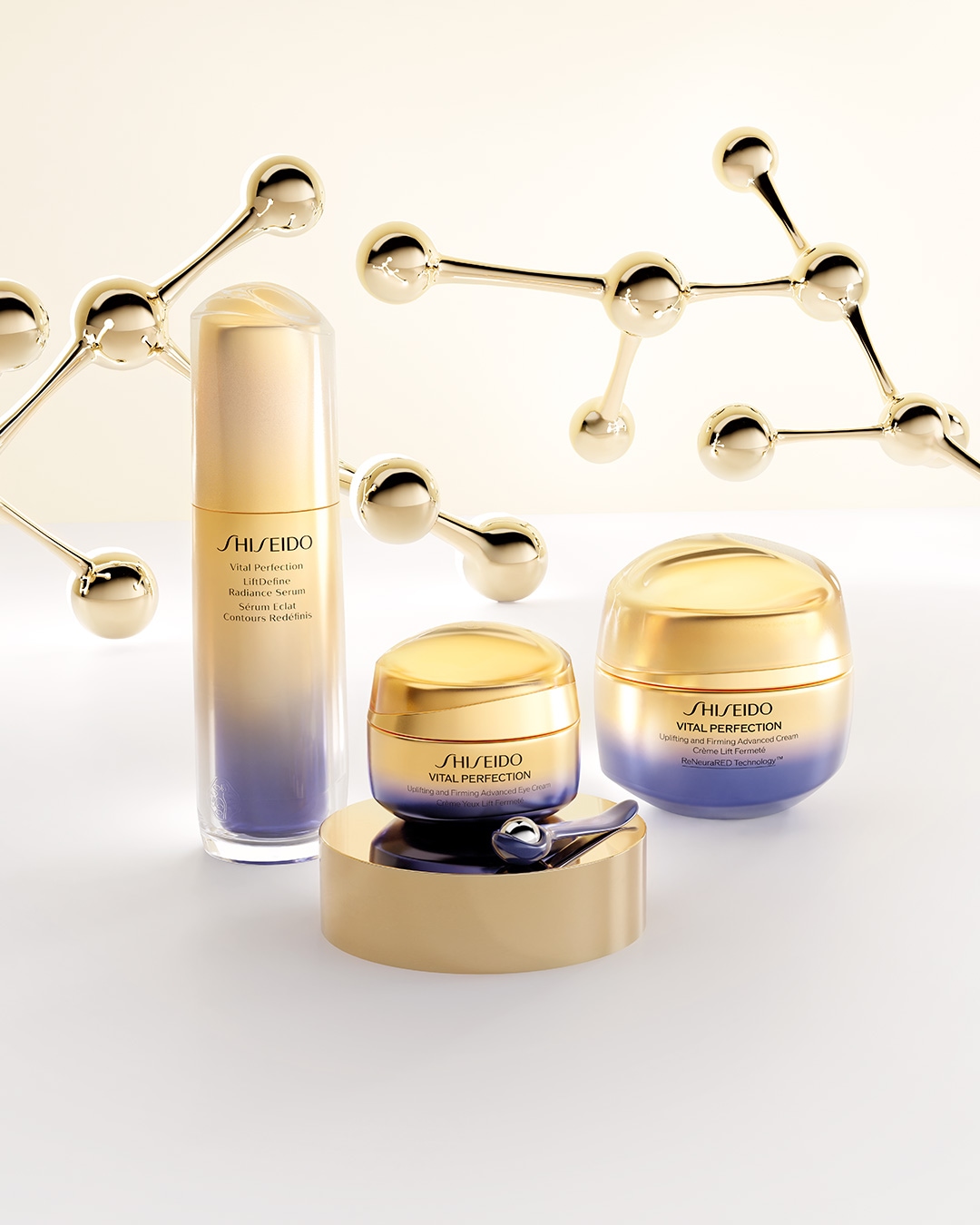 Descubre Shiseido Vital Perfection: sérum, crema para ojos y crema facial en envases dorados y morados, realzados con estructuras moleculares doradas.
