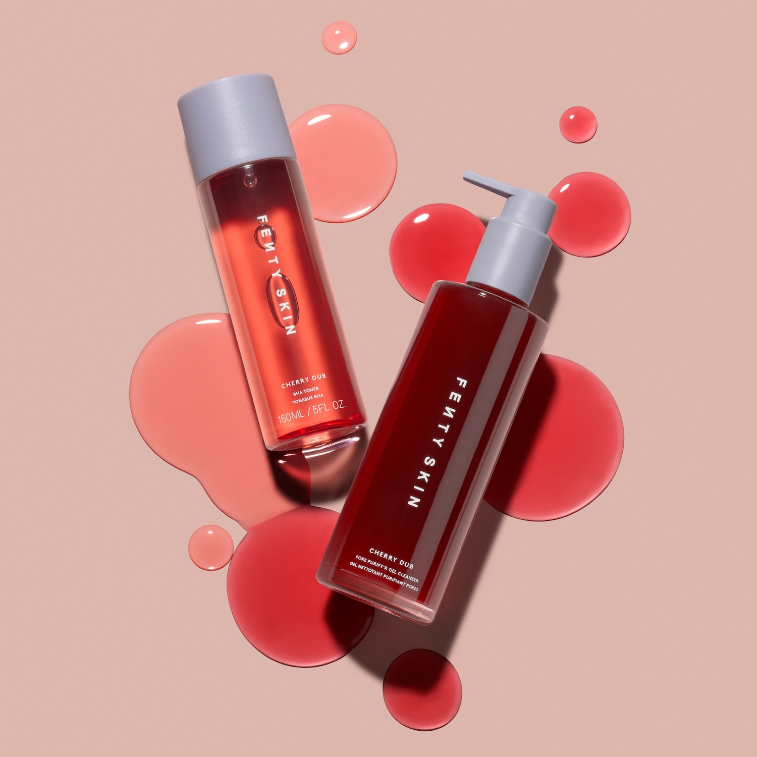 Twee Fenty Skin Cherry Dub-producten, een BHA-toner en een poriënreinigende gelreiniger, staan afgebeeld tegen een roze achtergrond met rode vloeistofdruppels.