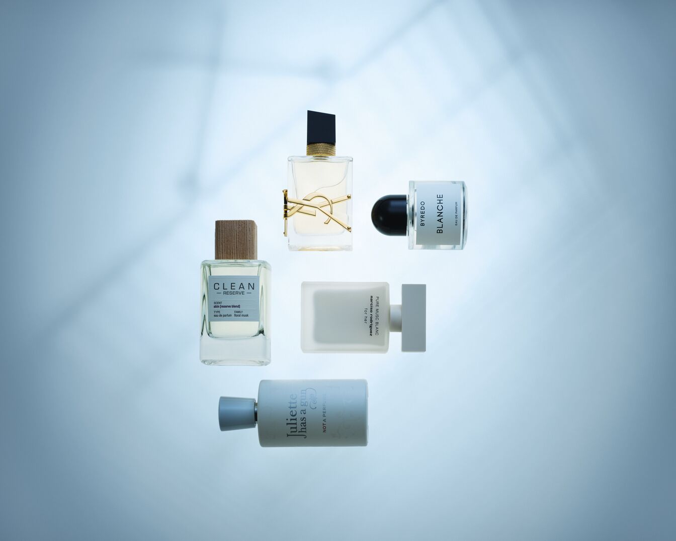 Verschiedene Parfümflakons von Marken wie CLEAN RESERVE, YSL, BYREDO, Narciso Rodriguez und Juliette has a gun sind auf einem hellblauen Hintergrund angeordnet.