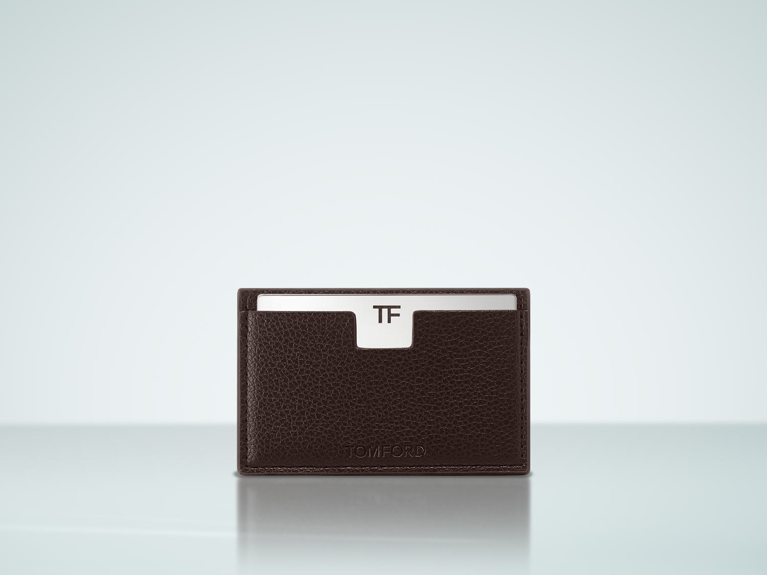 Voici un élégant porte-cartes Tom Ford en cuir marron foncé, orné du logo TF argenté, parfait pour ranger vos cartes avec style.