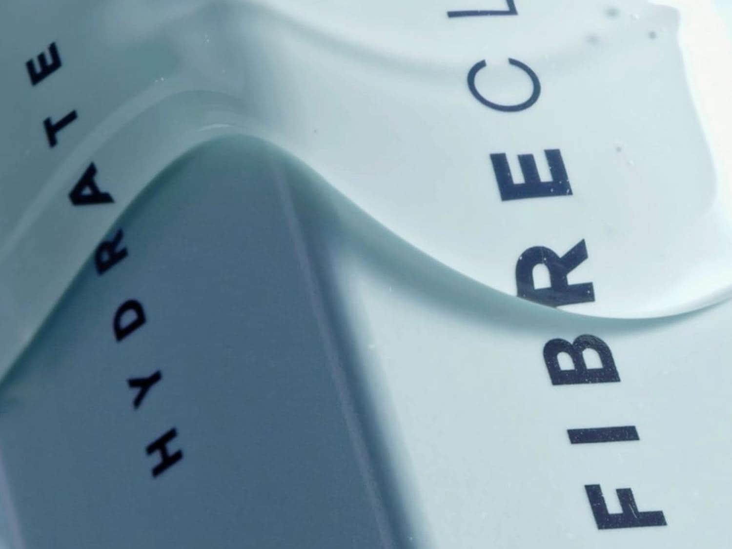 Zbliżenie na opakowanie produktu do pielęgnacji włosów w jasnoniebieskim odcieniu z napisem FIBRE CLINIX HYDRATE w kolorze czarnym.