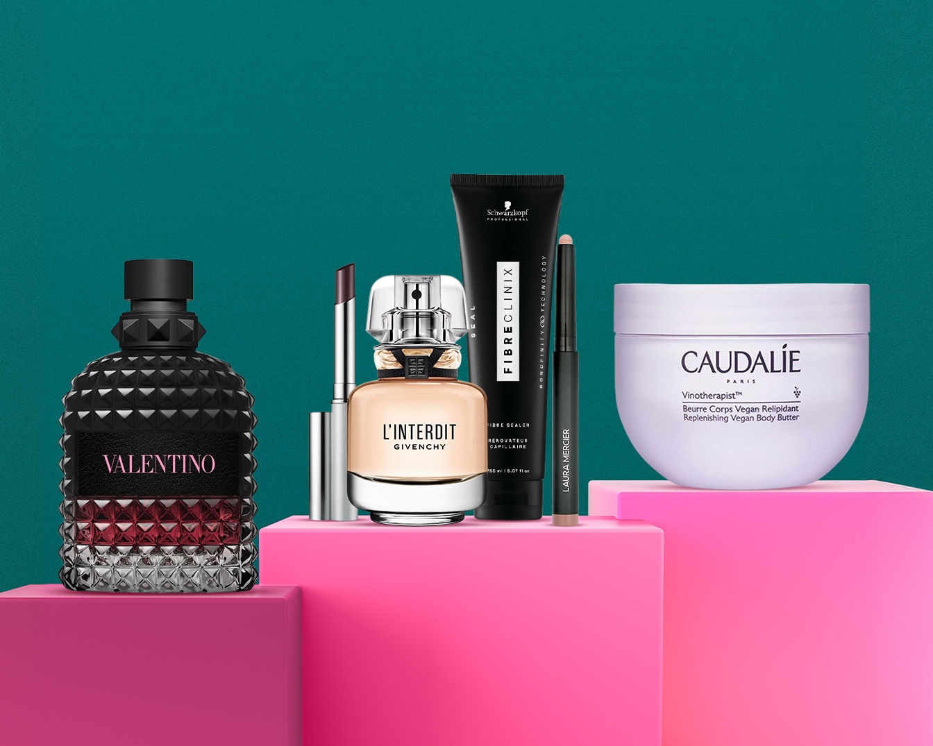Na różowych podestach prezentowane są różnorodne produkty kosmetyczne, w tym perfumy Valentino w czarno-czerwonym flakonie, szminka, perfumy Givenchy L'Interdit, produkty do włosów Schwarzkopf Fibre Clinix, kredka do oczu Laura Mercier i balsam do ciała Caudalie.