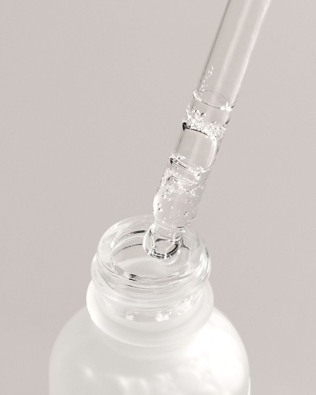 Découvrez le sérum dans son flacon blanc givré, avec une pipette transparente remplie d'une formule claire et hydratante, prête à revitaliser votre peau.