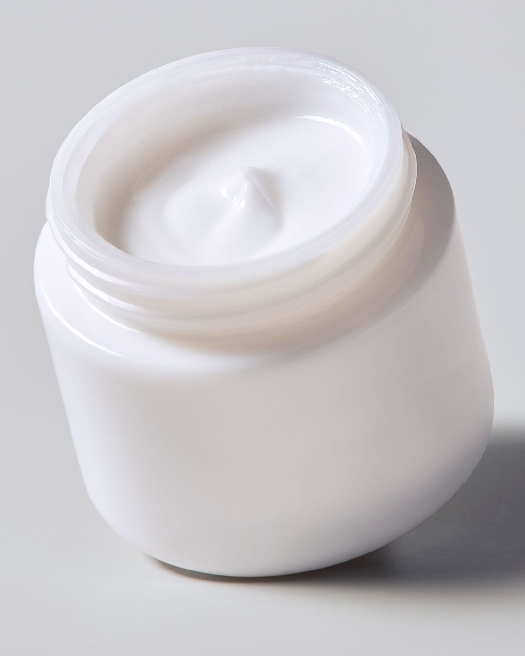 Découvrez un pot ouvert rempli d'une crème blanche et lisse, promettant une hydratation intense et une peau éclatante.