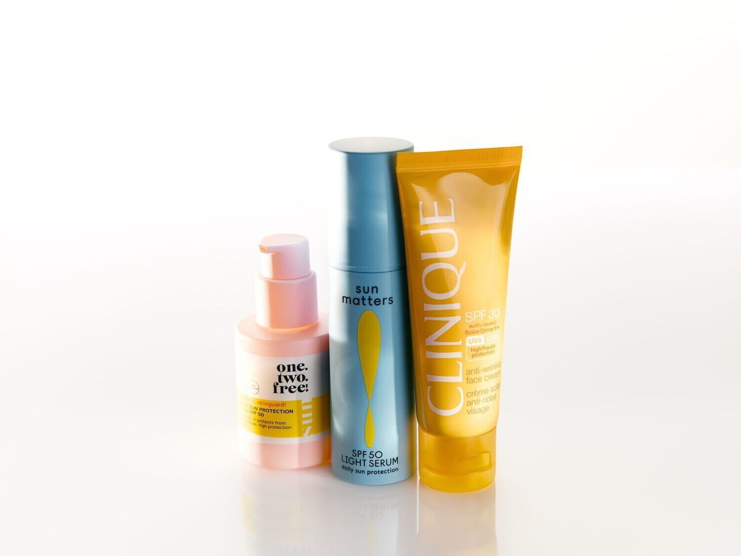 Trys apsaugos nuo saulės priemonės: rausvas losjonas one.two.free!, mėlynas serumas Sun Matters SPF 50 ir geltonas Clinique kremas nuo raukšlių su SPF 30.