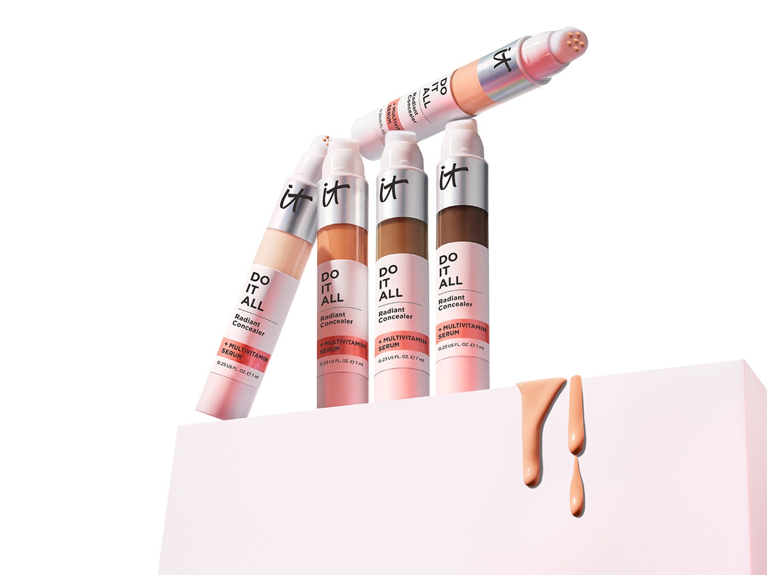 Kolekcja korektorów IT „Do It All Radiant Concealer” w różnych odcieniach, od jasnego beżu po głęboki brąz, każdy z aplikatorem i formułą z serum multiwitaminowym.
