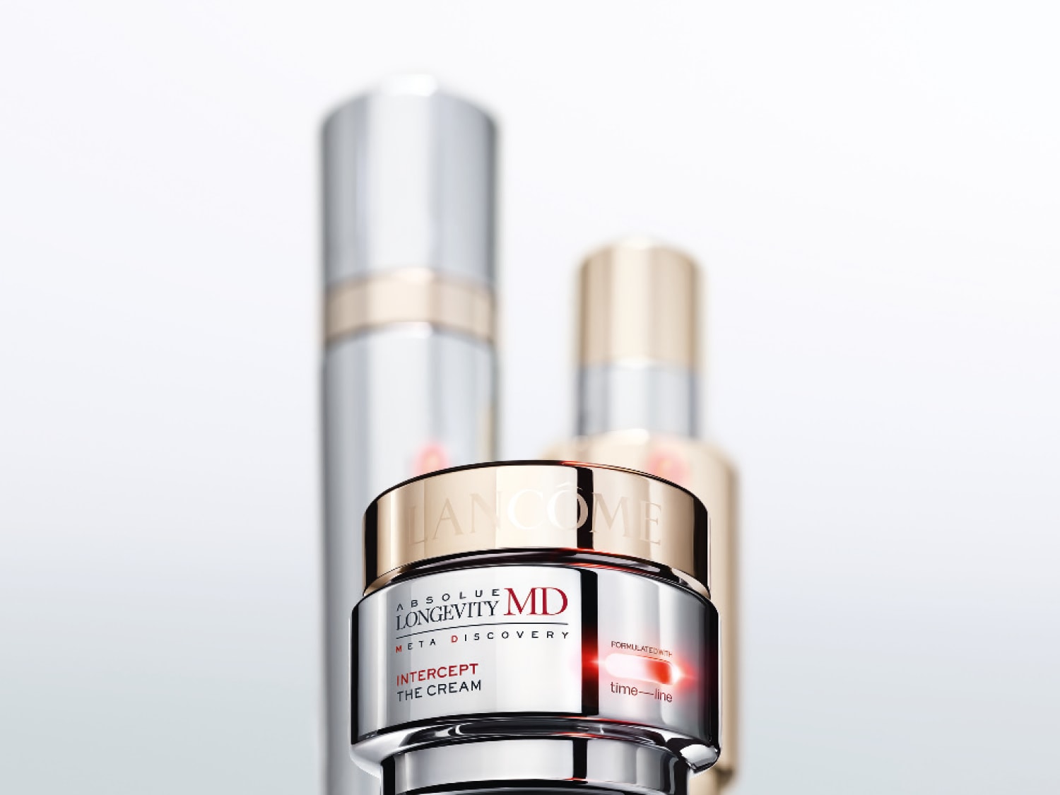 Srebrny słoiczek kremu Lancôme Absolue Longevity MD Intercept The Cream z elementami w kolorze złotym i czerwonym na białym tle.