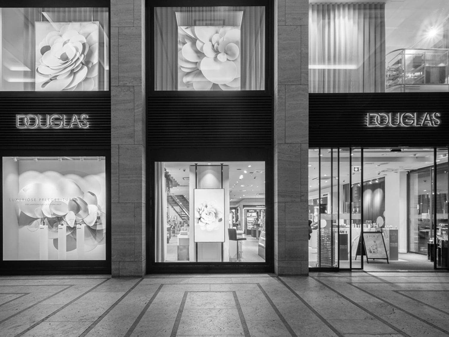 La fachada de Douglas irradia elegancia con sus escaparates adornados con motivos florales y la promesa de lujosos rituales de cuidado de la piel.