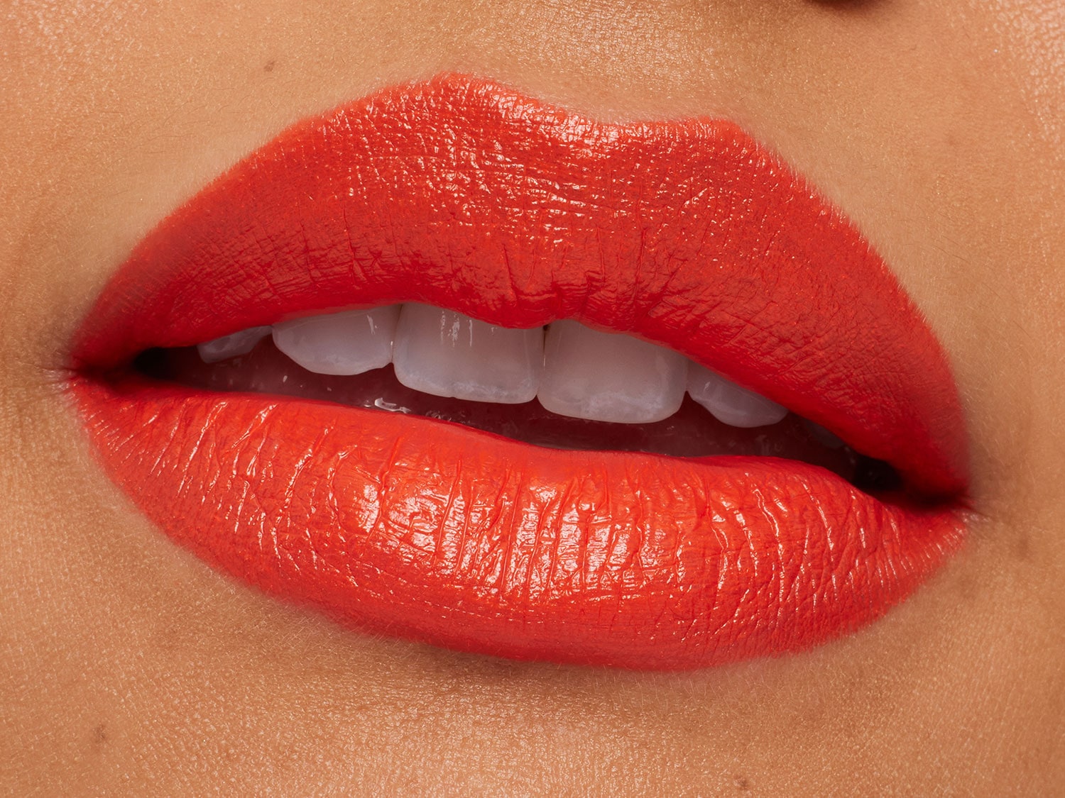 Glimmende, oranje lippenstift zorgt voor een gedurfde en levendige uitstraling.