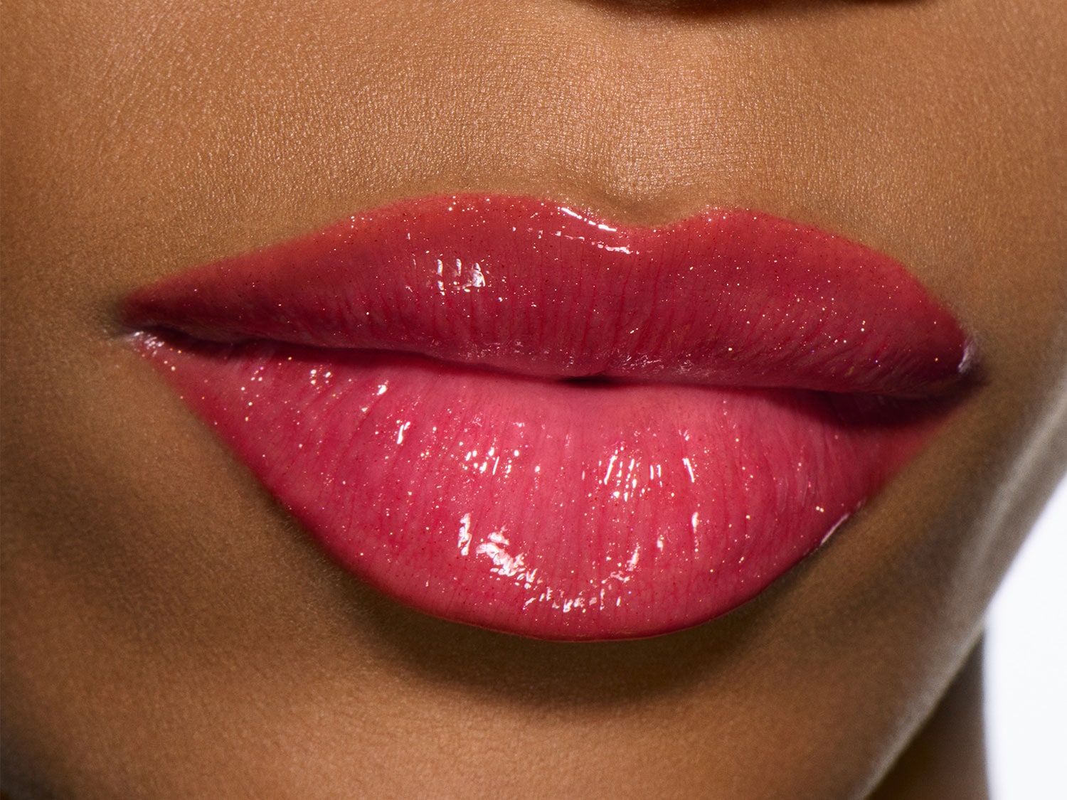 Close-up van volle lippen met glanzende, roze lipgloss, die een levendige en gehydrateerde uitstraling geeft.