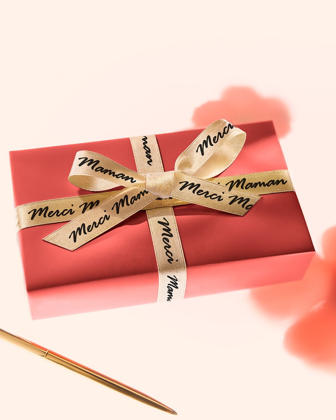 Un cadeau rouge élégant, orné d'un ruban doré portant les mots 'Merci Maman', prêt à exprimer votre gratitude avec style.