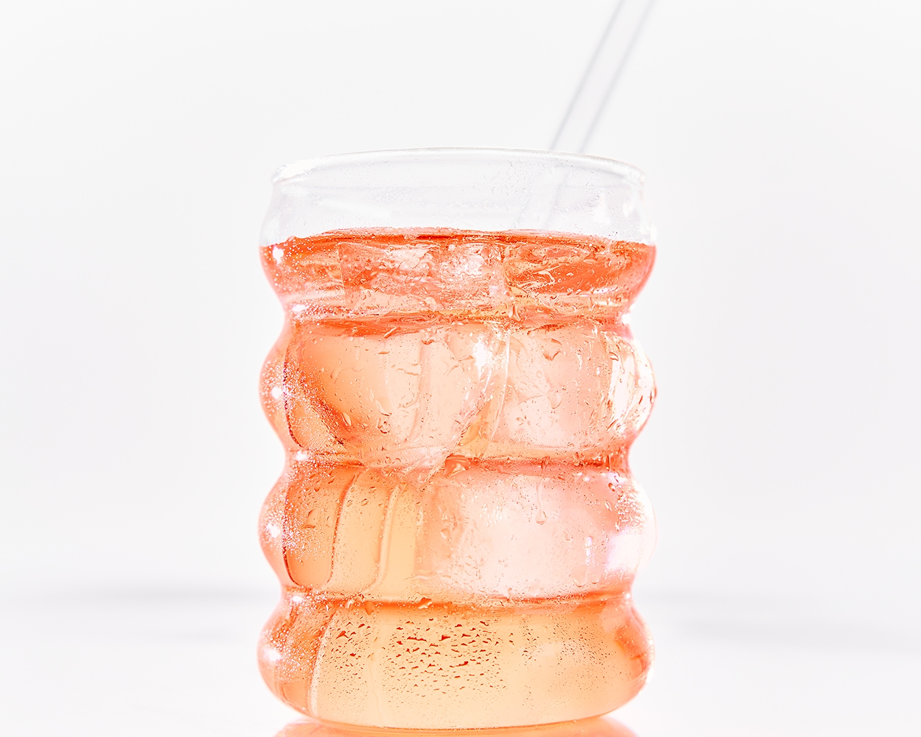 Ein erfrischendes Getränk in einem klaren Glas mit Eiswürfeln und einem Strohhalm, ideal für heiße Tage.