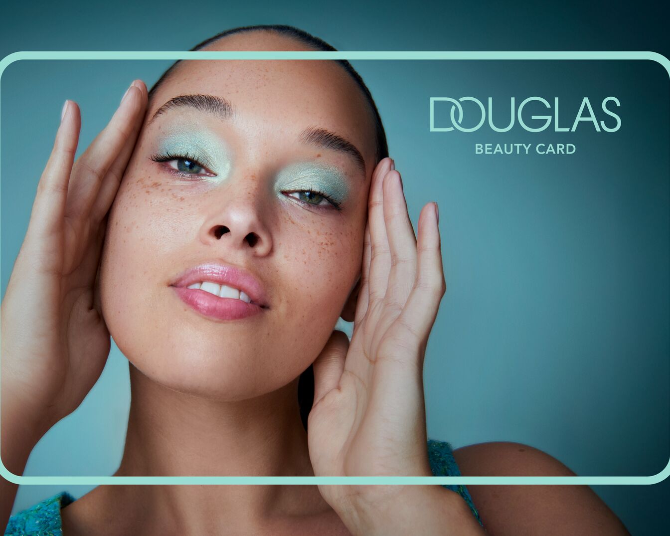 Portret kobiety z piegami i zielonym makijażem oczu na tle karty podarunkowej Douglas Beauty.