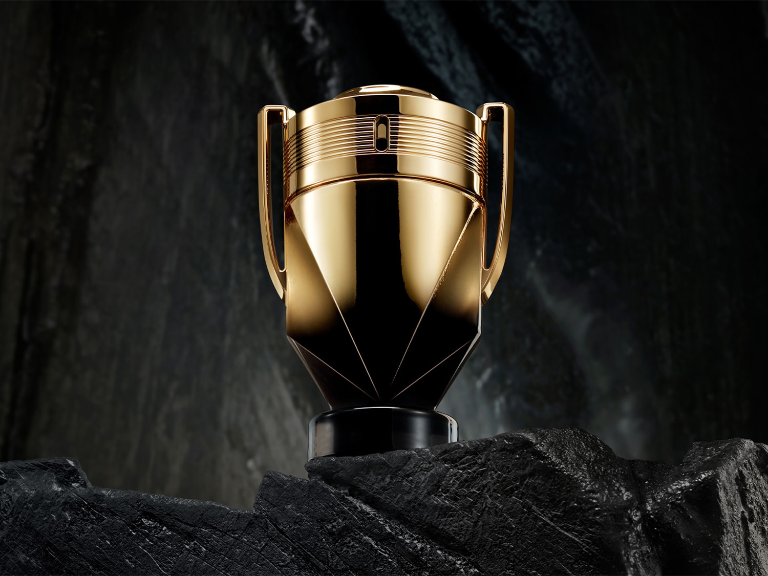 Le parfum Invictus de Paco Rabanne, présenté dans un flacon doré en forme de trophée, symbole de victoire et de puissance.