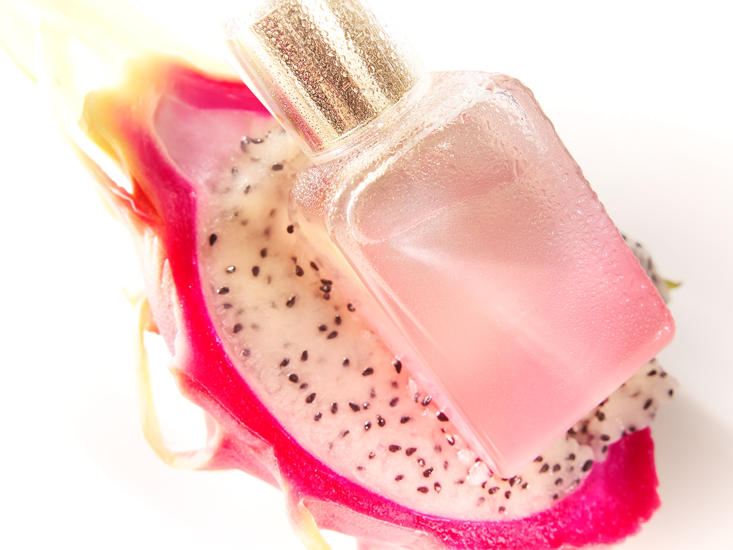Ein rosa getöntes Parfüm liegt auf einer aufgeschnittenen Drachenfrucht, die die Essenz eines tropischen Duftes einfängt.