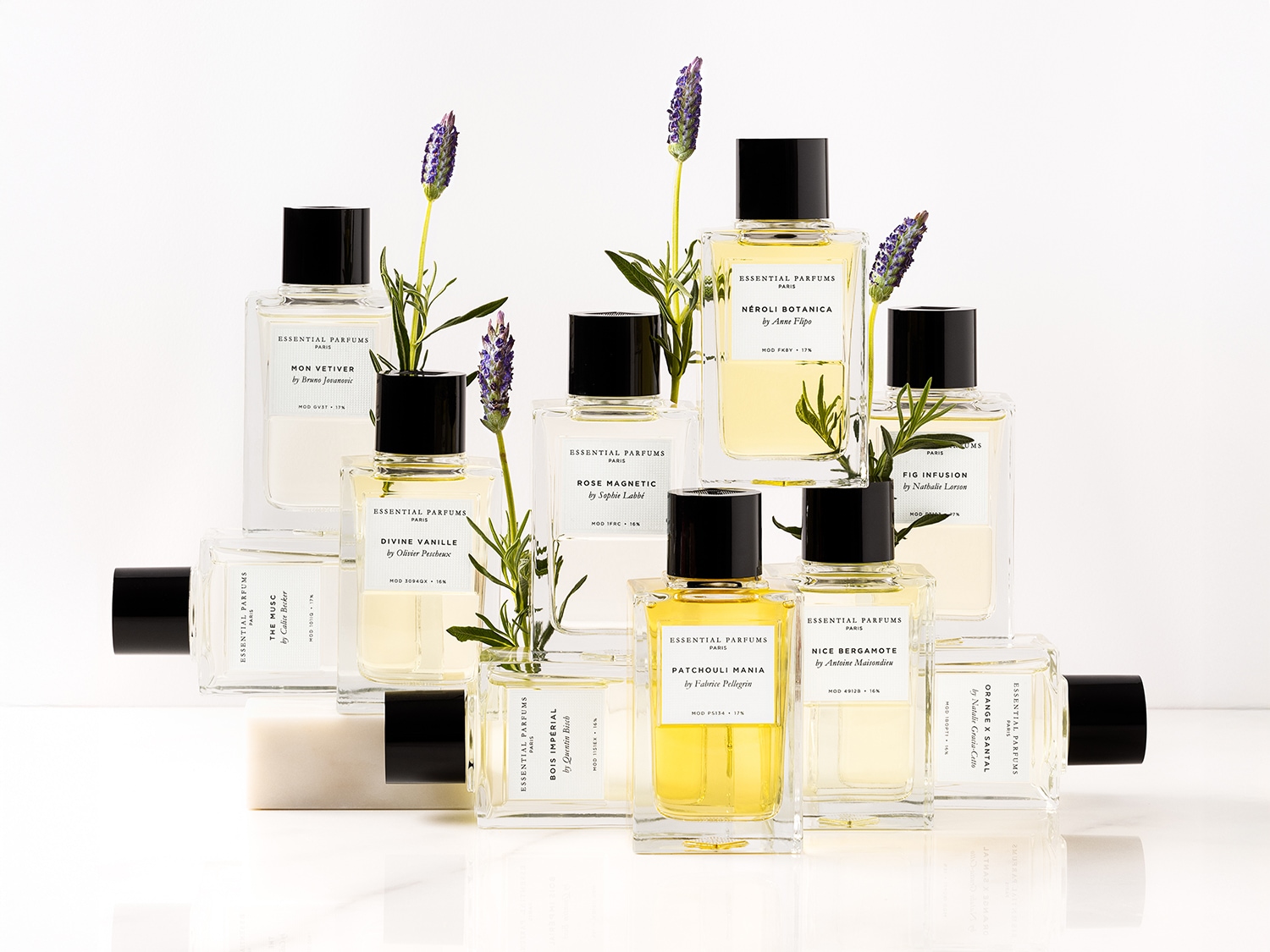 Eine Sammlung von Essential Parfums Paris Düften in durchsichtigen Flakons mit schwarzen Verschlüssen, verziert mit Lavendelzweigen.