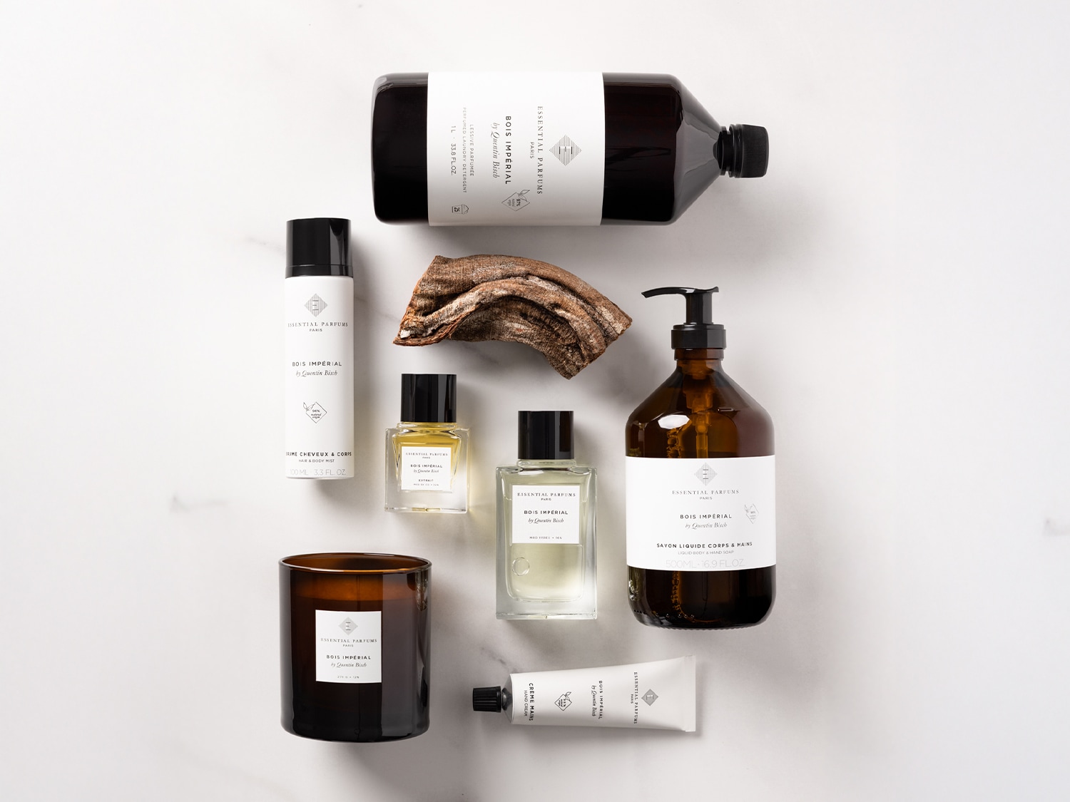 Eine Kollektion von Essential Parfums Bois Impérial Produkten, darunter Duft, Wäscheduft, Haar- und Körperspray, Flüssigseife, Handcreme und eine Duftkerze, die ein umfassendes Dufterlebnis bieten.