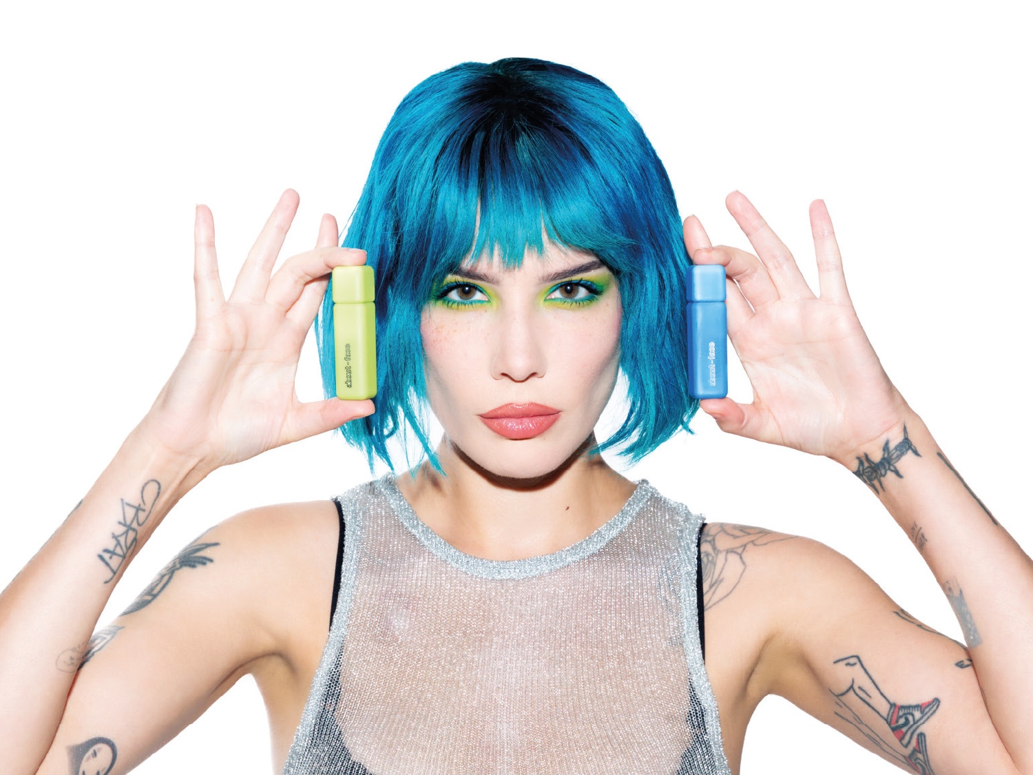 Una donna dai capelli blu mostra due prodotti About-Face: uno verde chiaro e uno blu, evidenziando la varietà e lo stile del marchio.