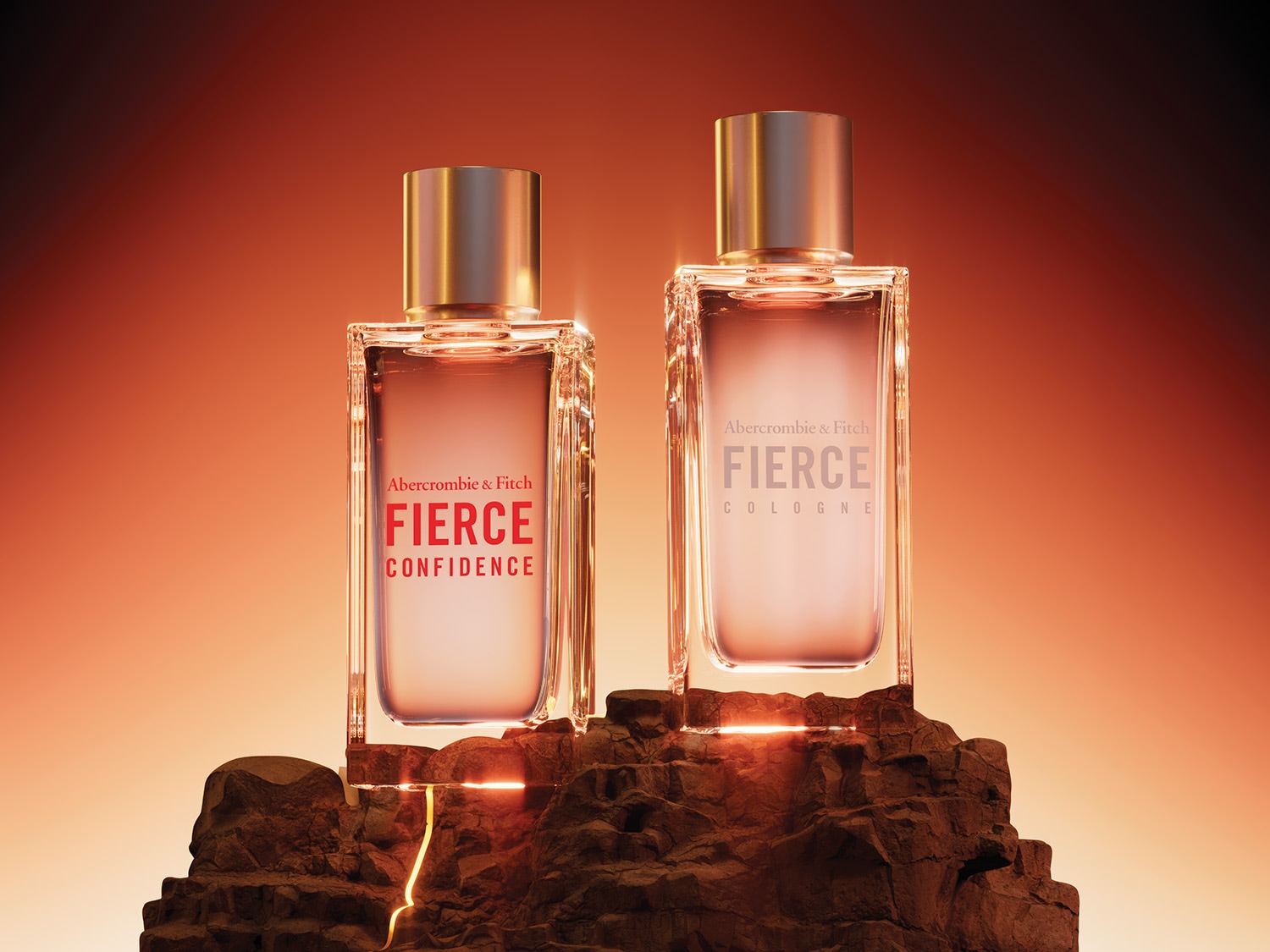 Due flaconi di profumo Abercrombie & Fitch Fierce, uno con etichetta rossa "Confidence" e l'altro con etichetta grigia "Cologne", sono posizionati su rocce scure con una luce arancione che li illumina da dietro.