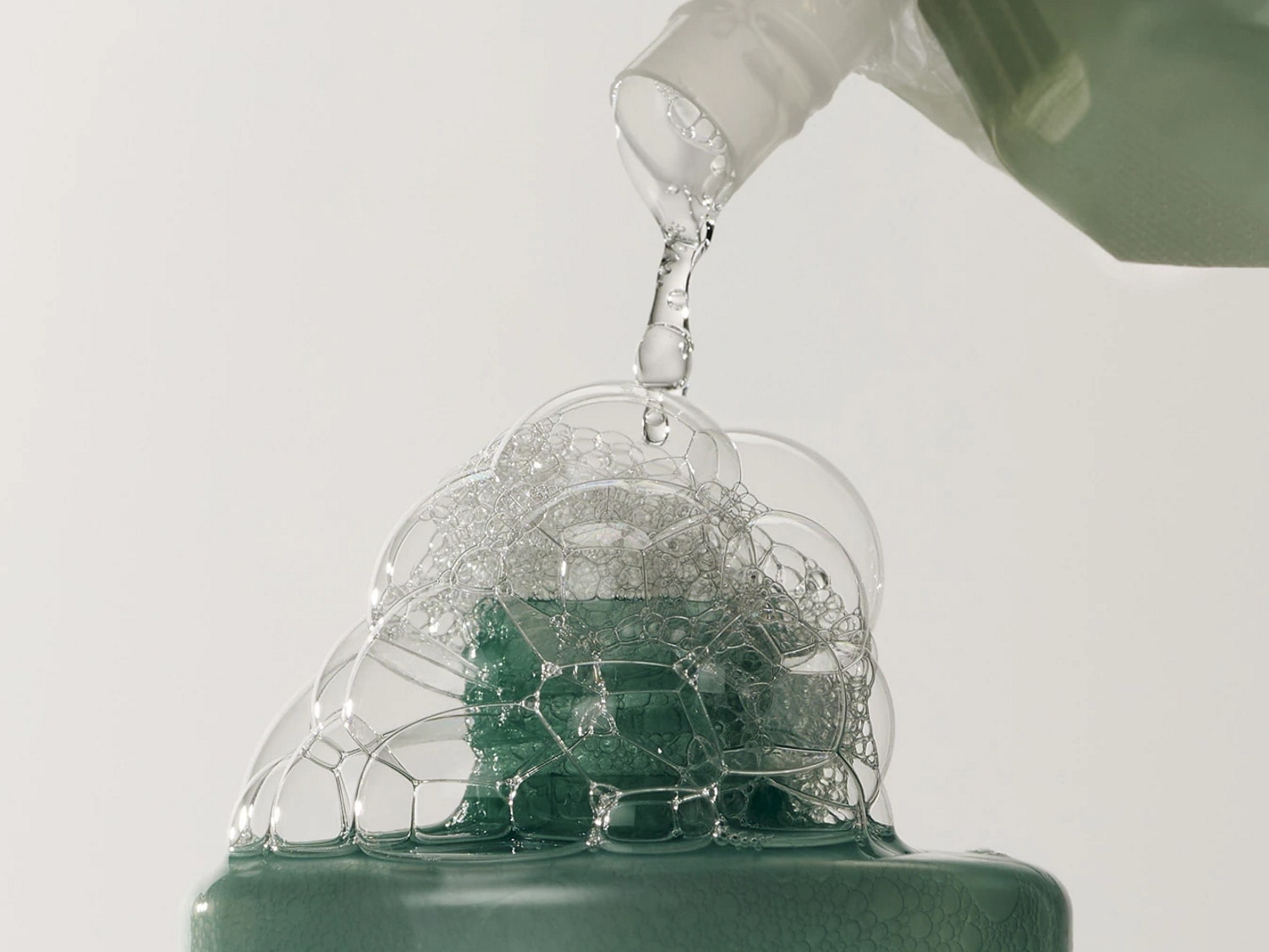 Le liquide vert mousseux est versé dans une bouteille, créant une cascade de bulles claires et brillantes.