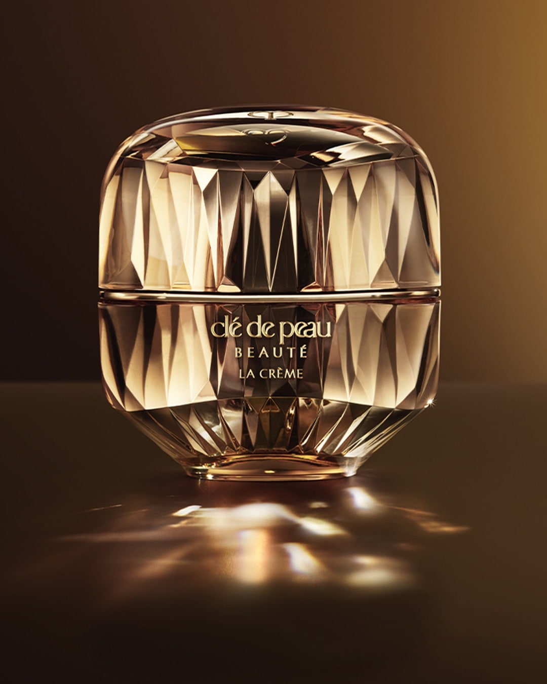 Nahaufnahme von Clé de Peau Beauté La Crème in einem goldenen, facettierten Tiegel, der Eleganz und Luxus ausstrahlt.