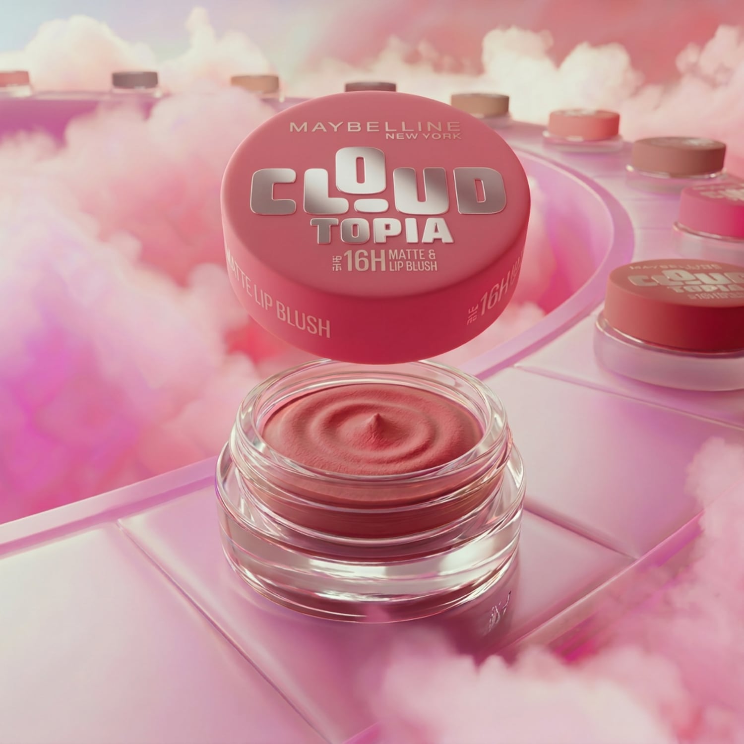 Découvrez le blush à lèvres mat Maybelline Cloud Topia 16H, présenté dans un pot transparent avec un couvercle rose portant le nom du produit en lettres argentées.