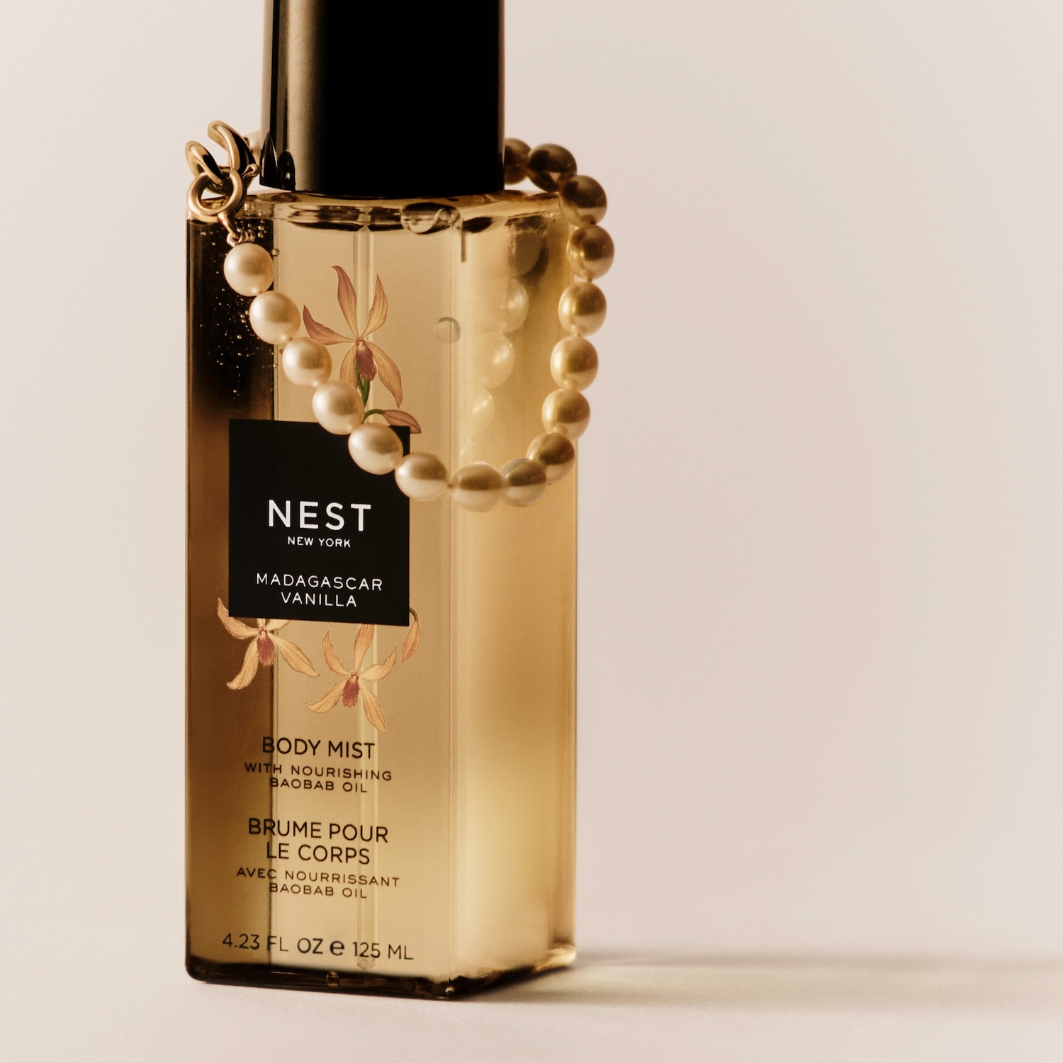 „Nest New York Madagascar Vanilla“ kūno dulksna su maitinamuoju baobabų aliejumi, 125 ml, yra skaidriame buteliuke su juodu dangteliu ir perlamutriniu karolių vėriniu, apvyniotu aplink buteliuko kaklelį.