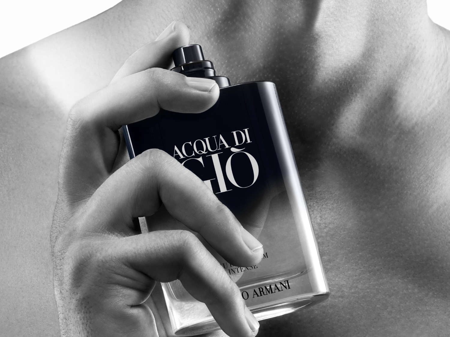Egy férfi tartja az Acqua di Gio parfümöt, melynek sötétkék és átlátszó üvege van, elegáns és friss illatot sugallva.