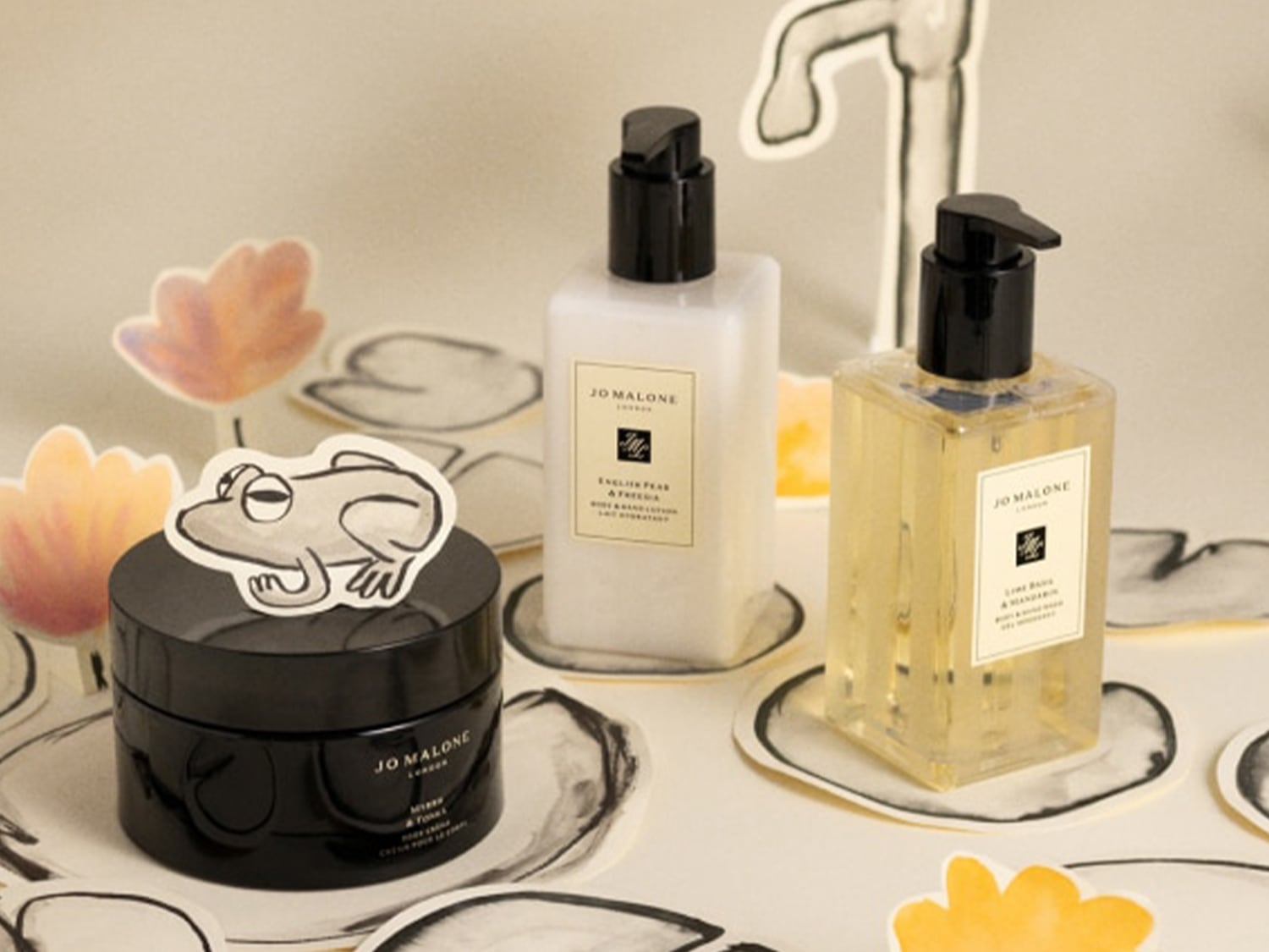 Tři produkty Jo Malone London: černý krém na tělo s žabkou, bílé tělové mléko a žlutá mycí emulze, vše s černými pumpičkami.