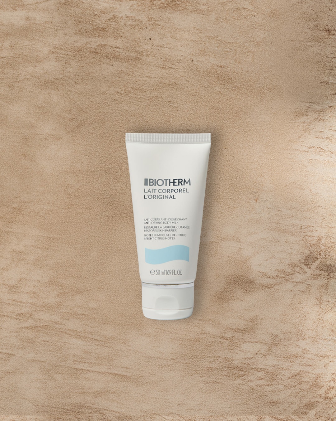 Die weiße Tube Biotherm Lait Corporel L'Original Anti-Trocken-Körperemulsion mit hellblauen Akzenten verspricht die Wiederherstellung der Hautbarriere und enthält leuchtende Zitrusnoten.