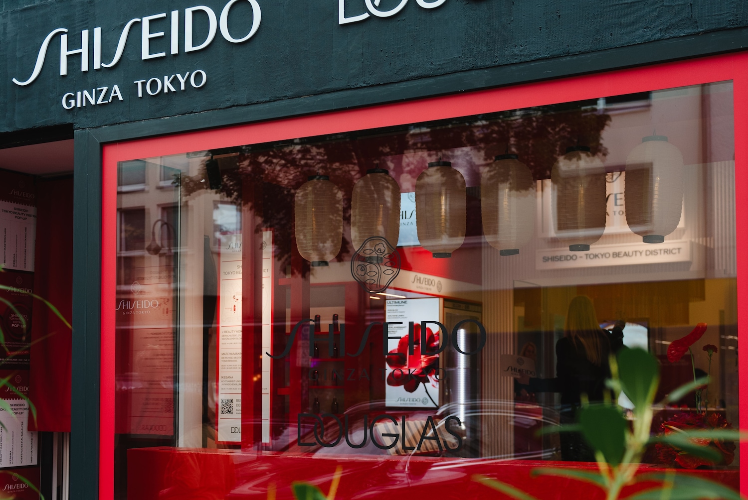 Blick auf ein Douglas-Schaufenster mit Shiseido Ginza Tokyo-Produkten, dekoriert mit japanischen Laternen, die ein einladendes Ambiente schaffen.
